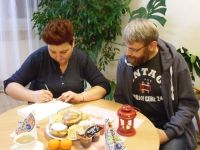 mężczyzna patrzy na kobietę podpisującą książkę